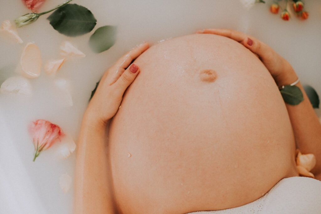 pregnant woman sitting on bathtub