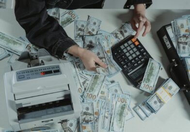 person holding dollar bills while using a calculator